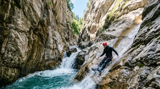 Un canyoneur glisse sur un toboggan naturel creuse dans la roche d'un canyon alpin, entoure de parois rocheuses et d'une eau turquoise.